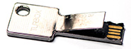 A monolithic flash drive encased in a metal case shaped as a key.