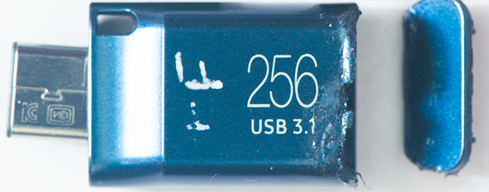 Blue USB 3.1 flash drive labeled '256' (256 GB) with cap at the end, partially inserted into a USB connector edge open on the left side.