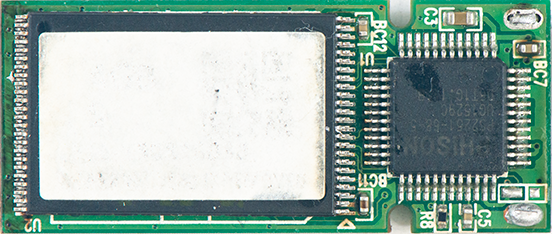 Close-up of a green printed circuit board featuring a large white rectangular component beside a black square integrated circuit on the right.